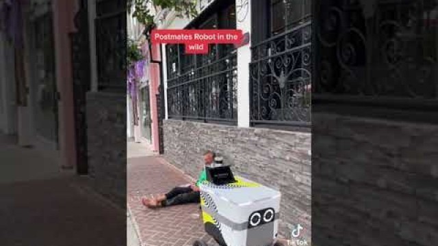 'Autonomous/Self driving Postmates food robot carefully maneuvers around a homeless man'